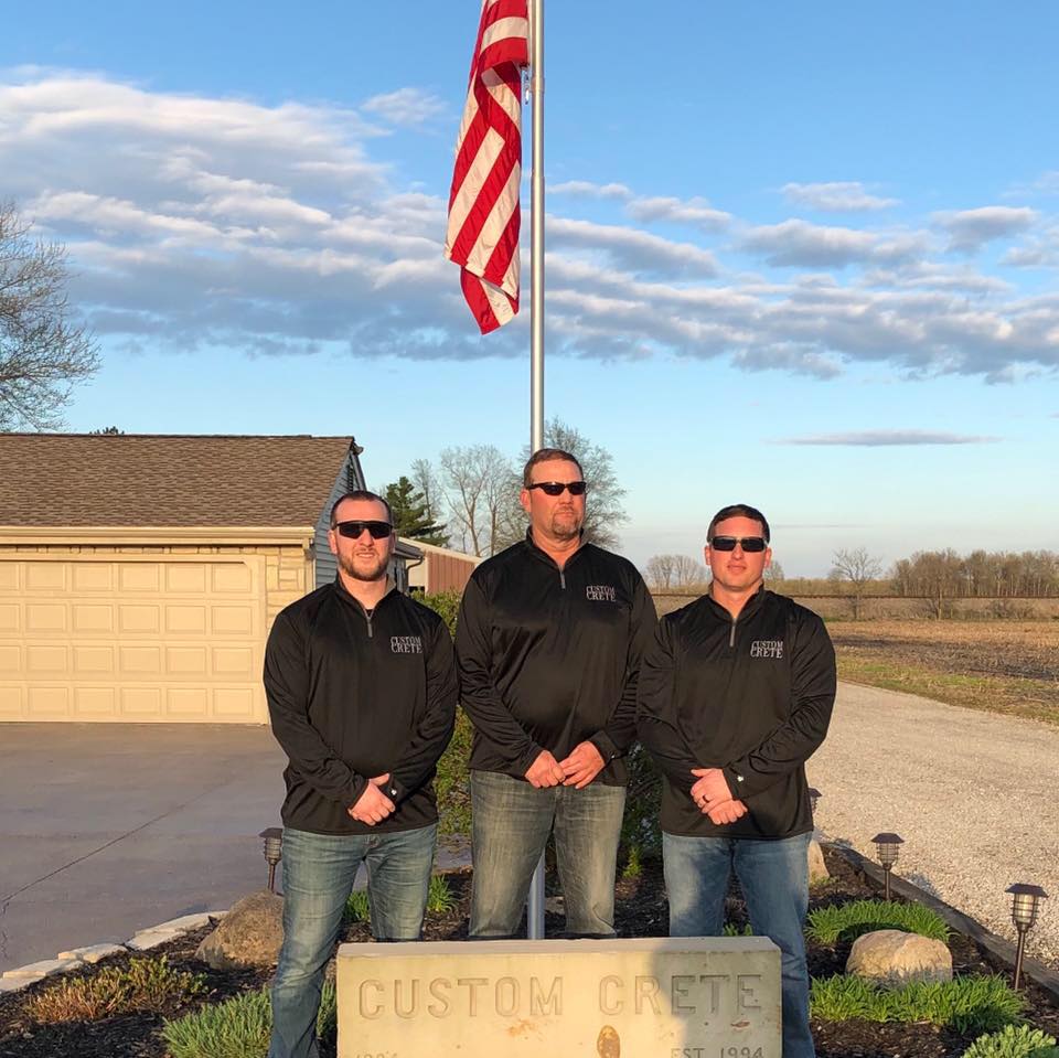 Custom Crete crew sitting together on a stamped compass-star concrete medallion