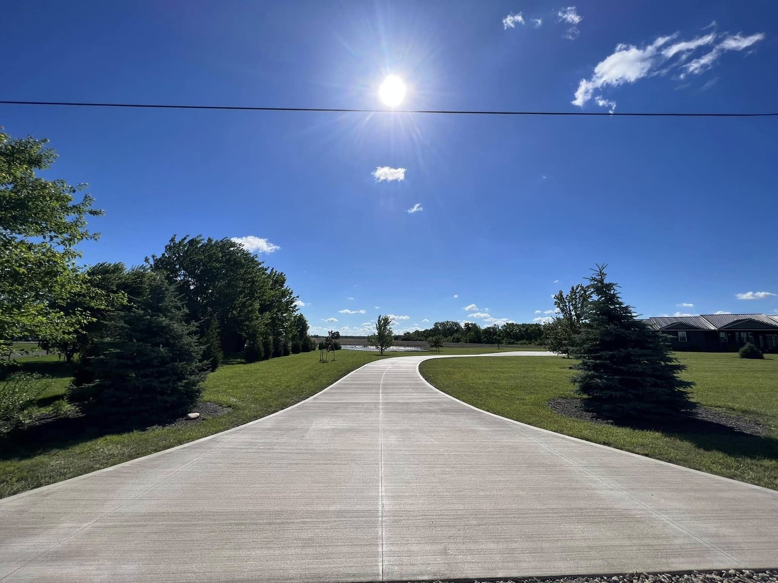 Long residential concrete driveway under a clear blue sky