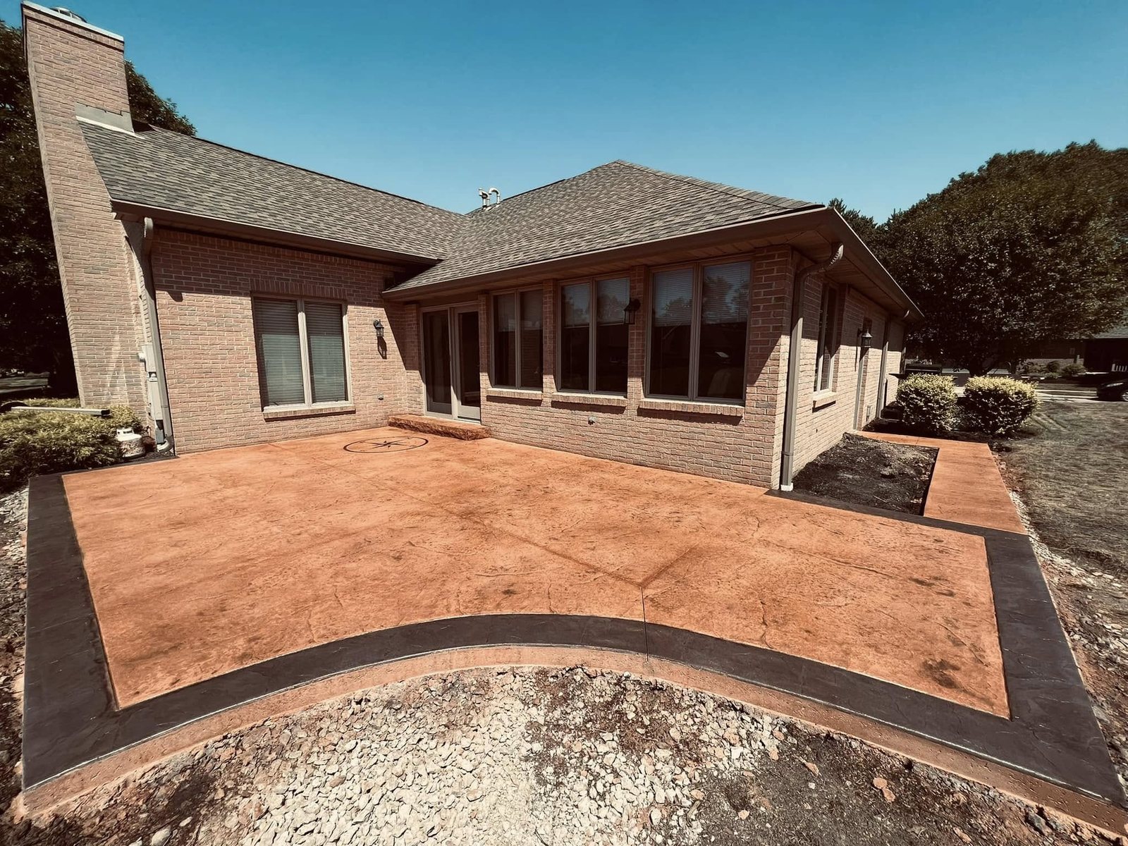 Tan stamped concrete back patio with a herringbone brick pattern