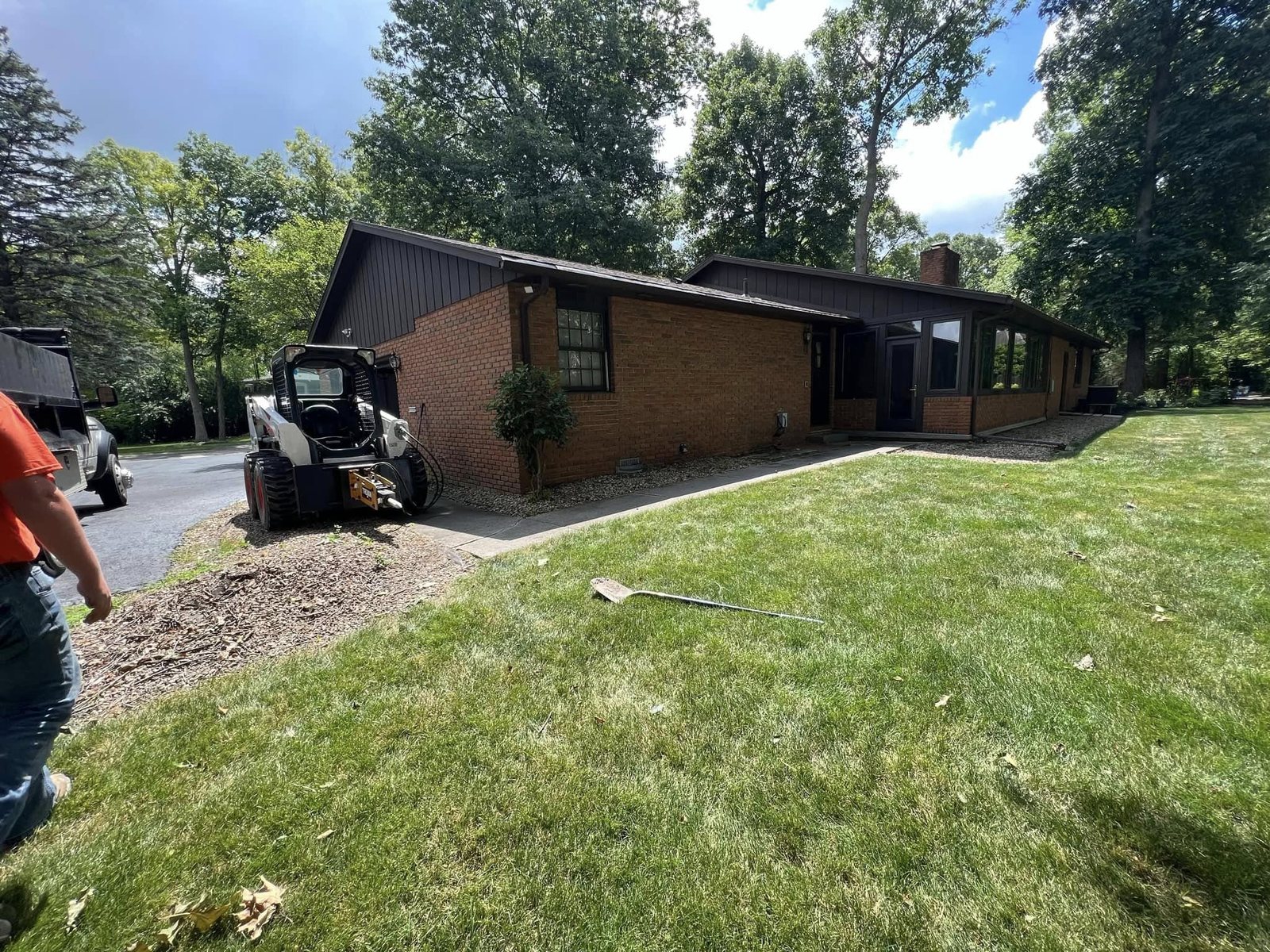 Brick ranch home with a bare dirt area before the new patio was poured