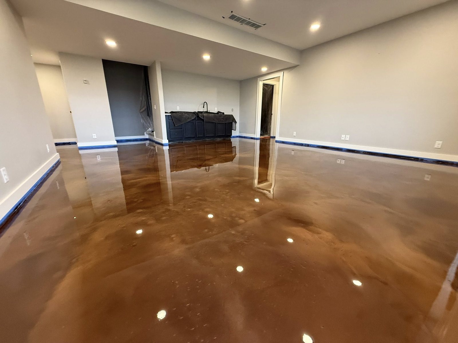 Glossy copper-brown metallic epoxy floor in a finished basement with a bar.