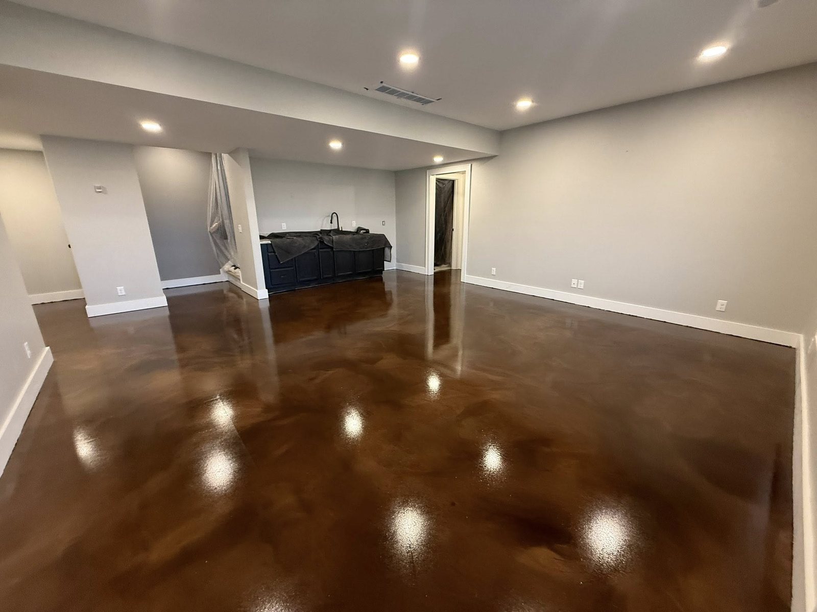 Glossy copper and brown metallic epoxy floor in a finished basement living area.