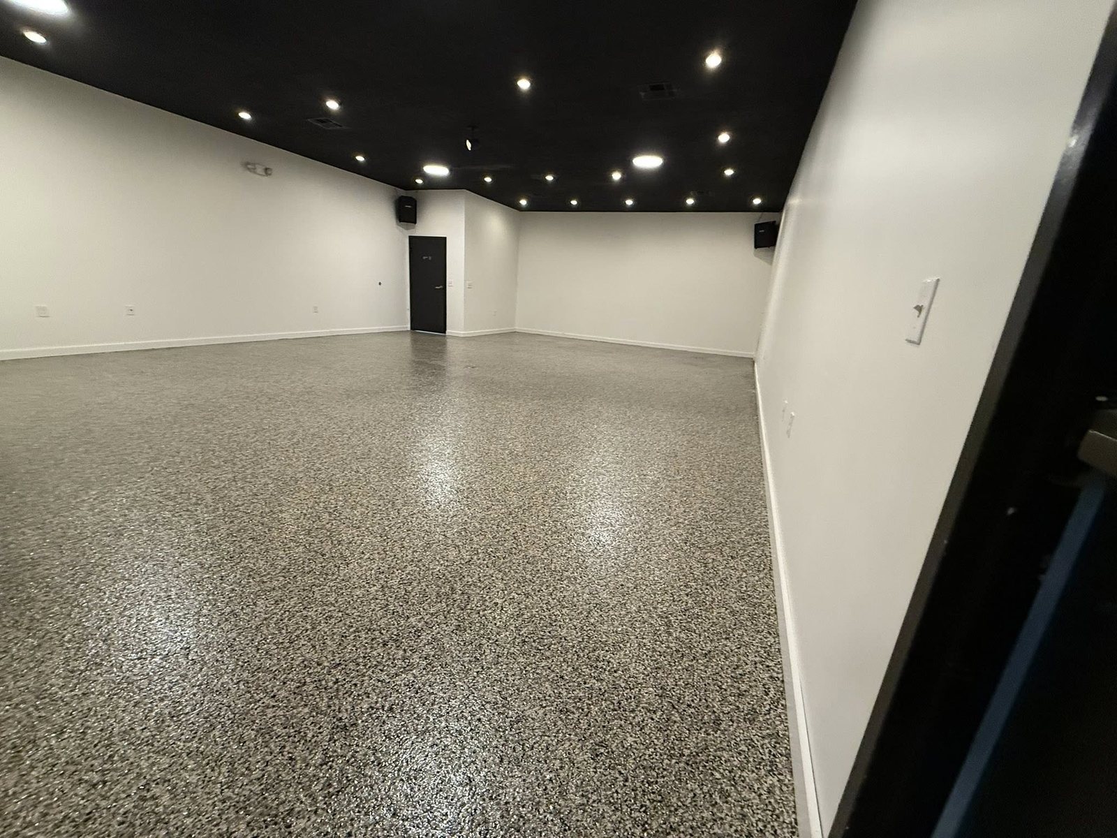 Gray and black flake epoxy floor in a commercial room with white walls.