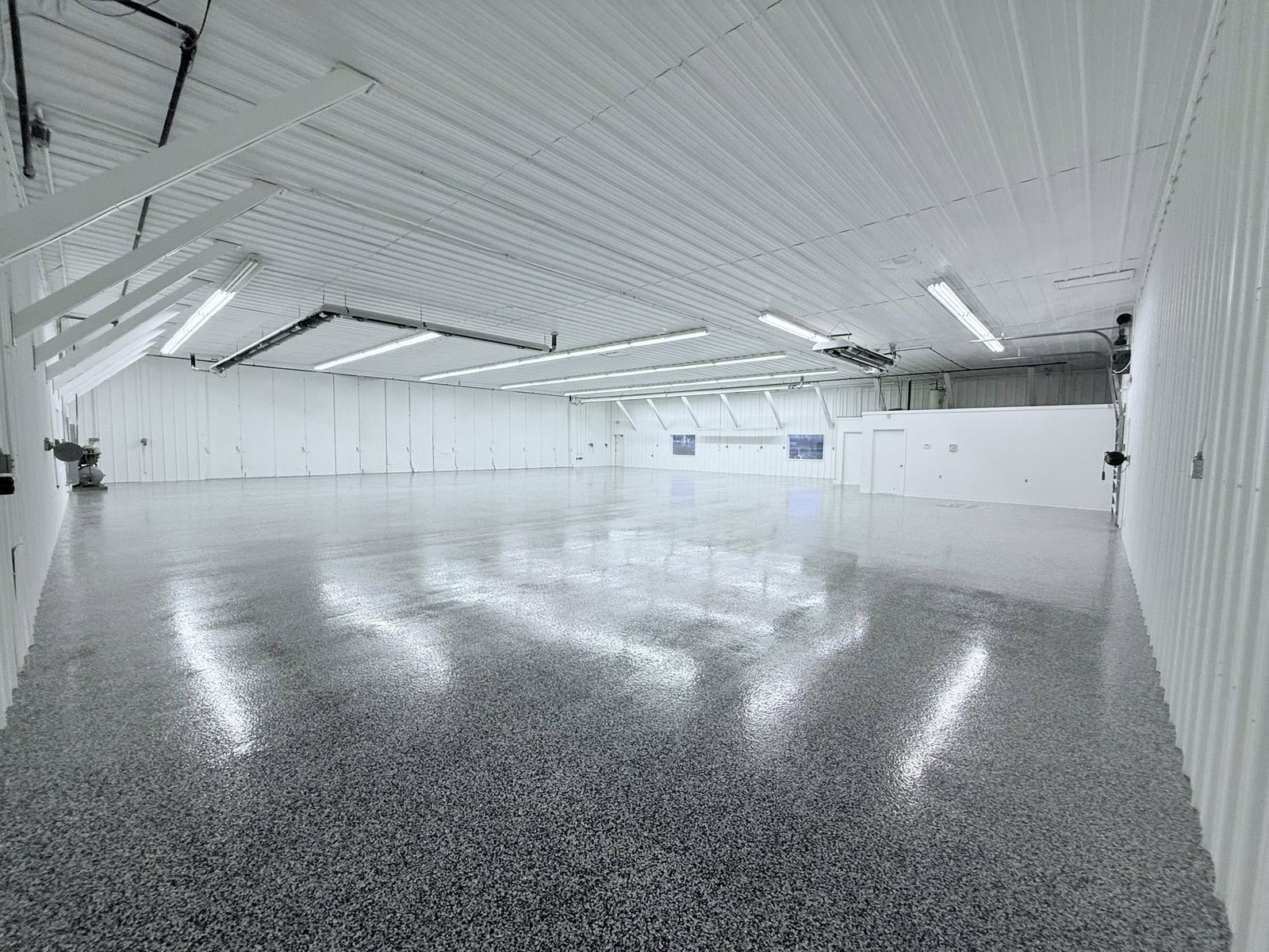 Glossy gray flake epoxy floor filling a spacious white metal building.