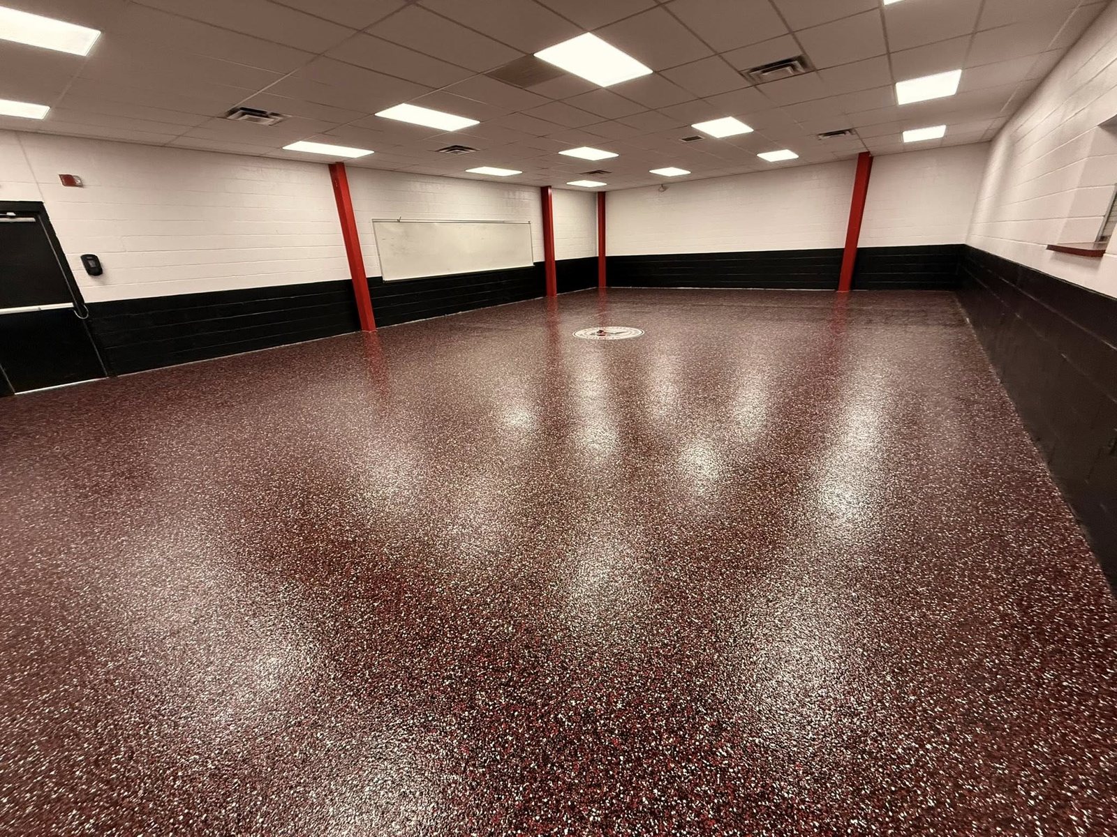 Glossy maroon and white flake epoxy floor in a large school room.