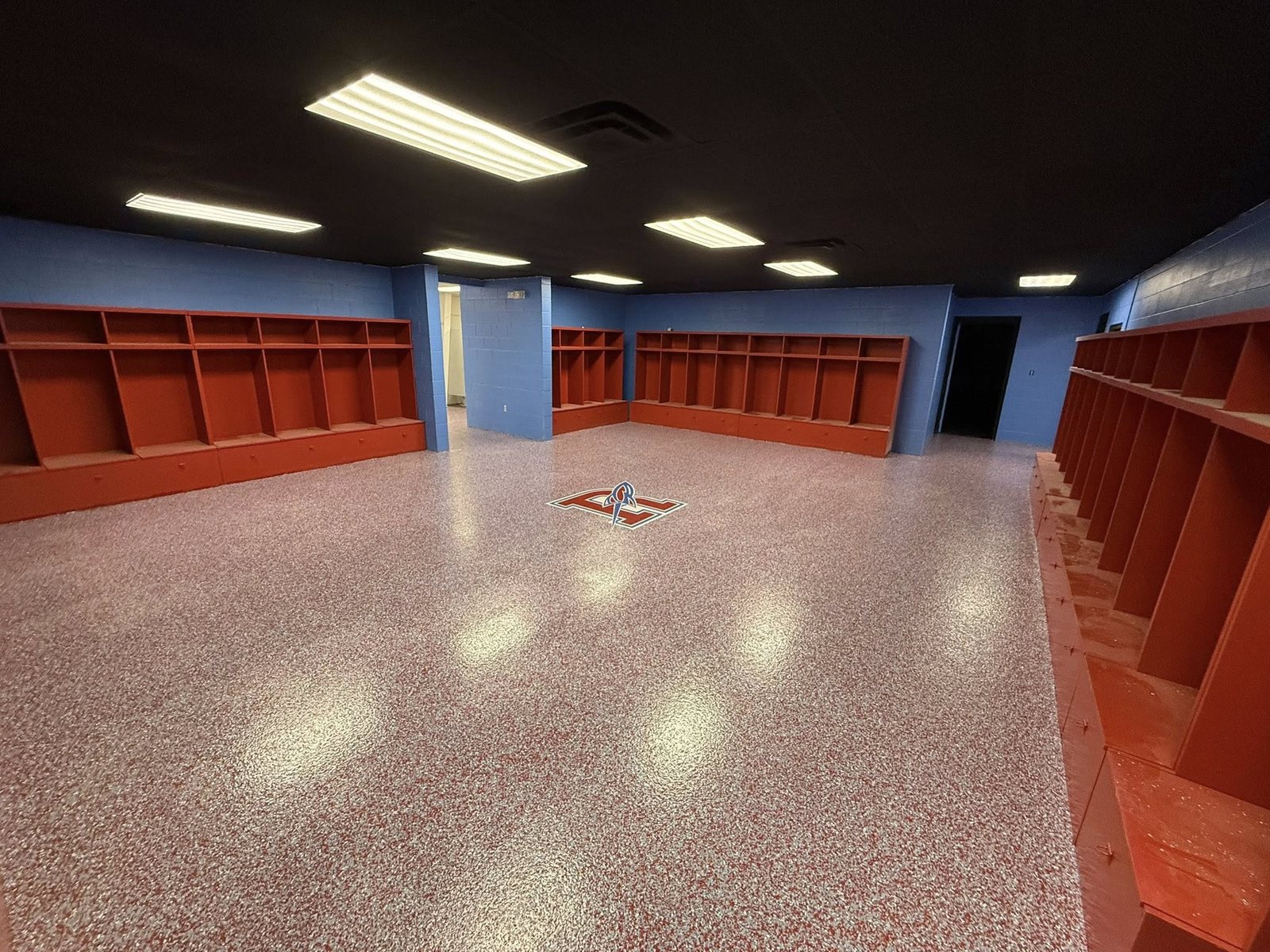 Red and tan flake epoxy floor in a blue locker room with orange cubbies.