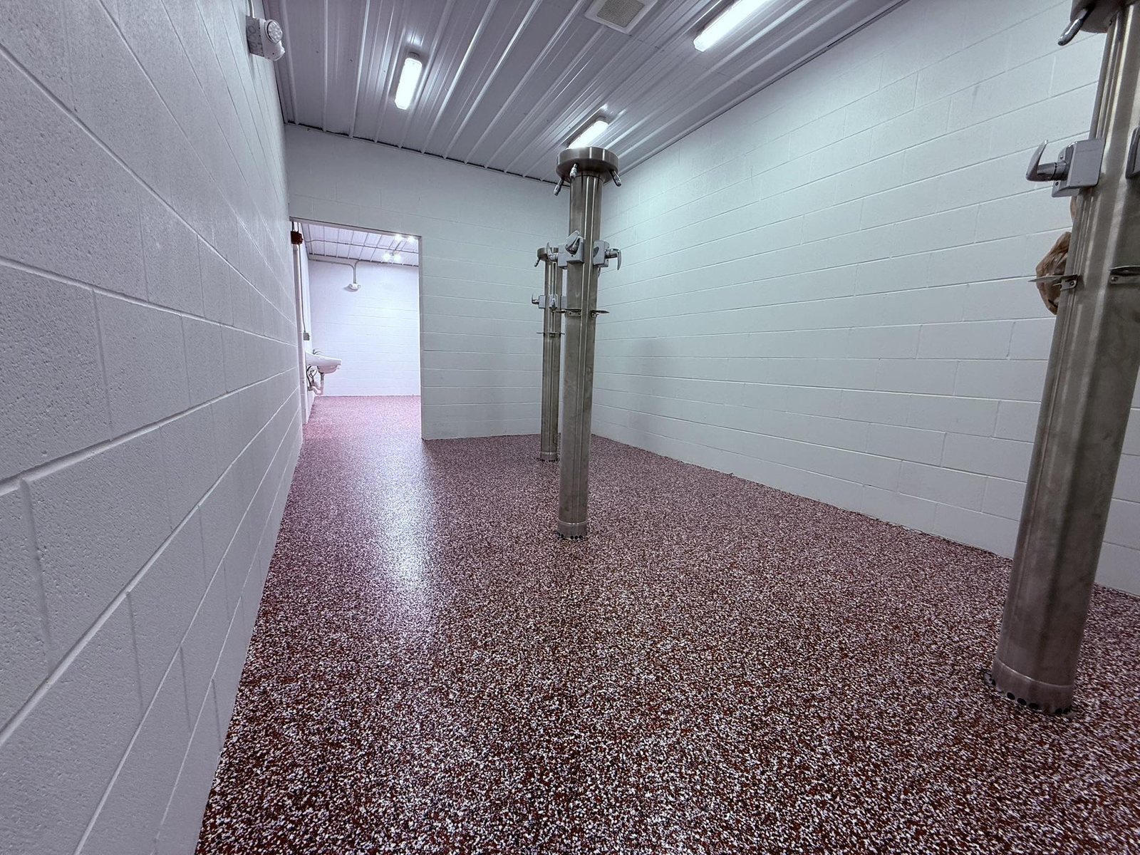 Glossy red and tan flake epoxy floor in a tiled washroom.
