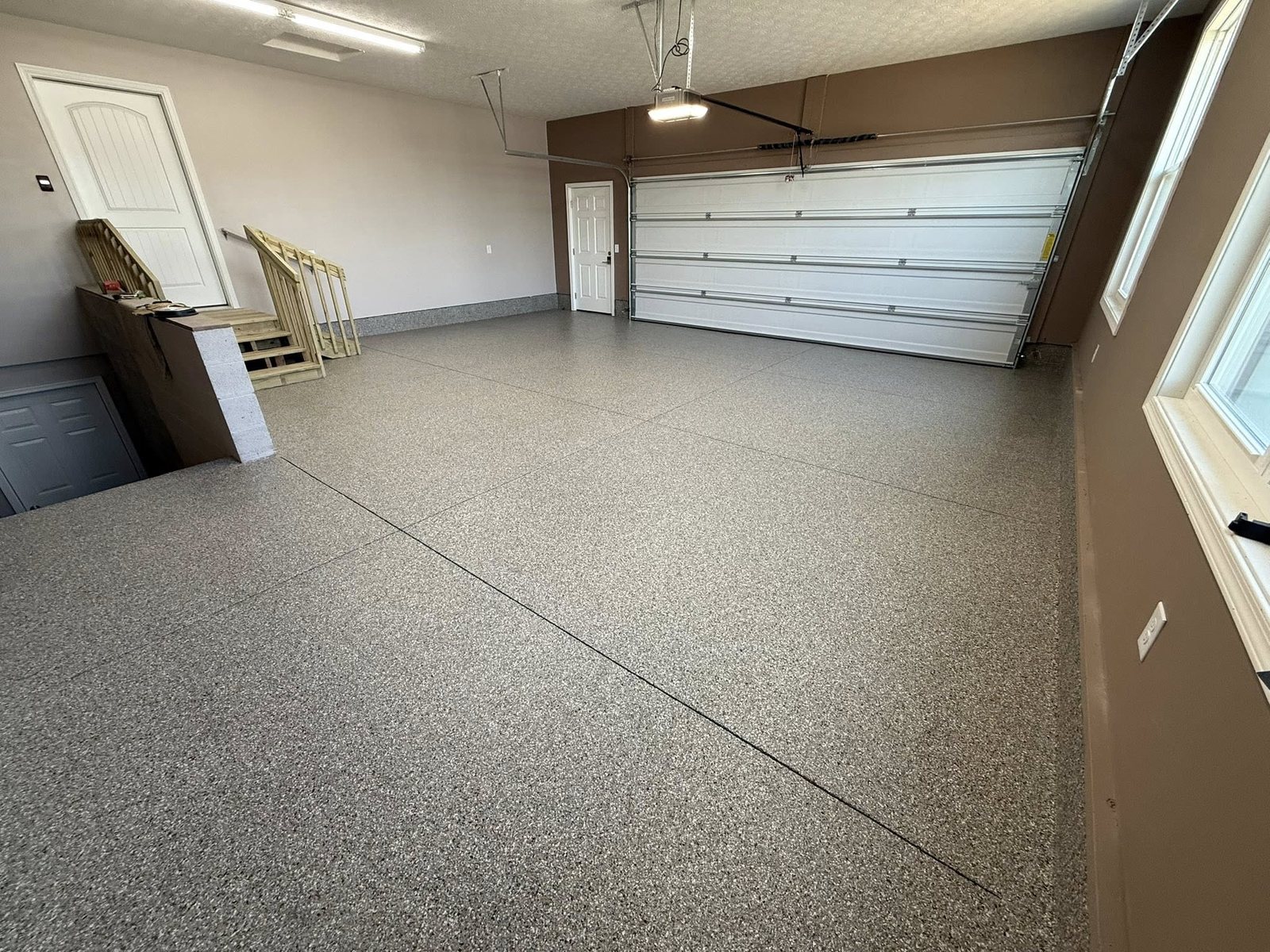 Tan flake epoxy garage floor with a glossy, durable finish and white overhead door.