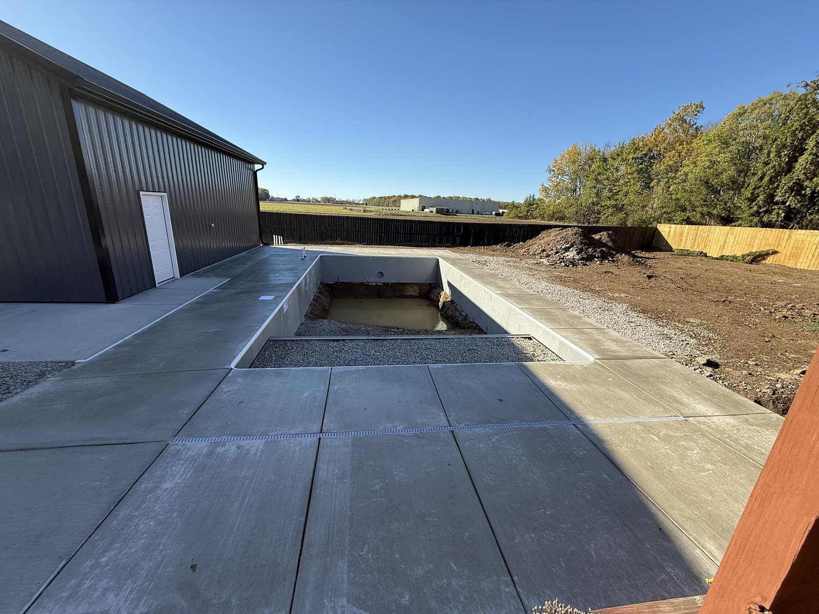 Finished broom-finished concrete pool deck and walkways under a blue sky.