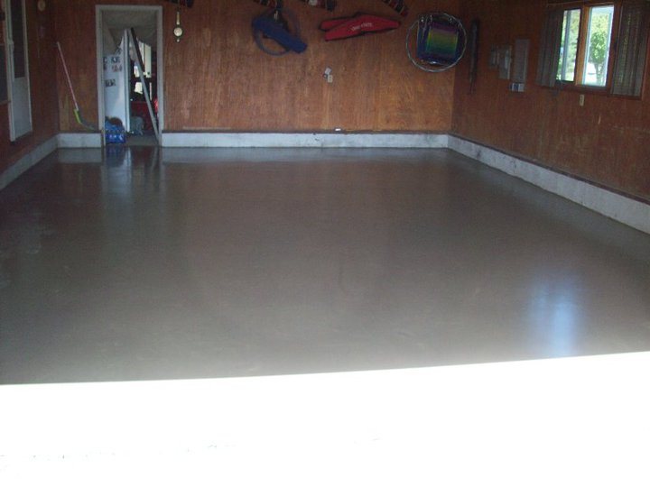 The same wood-paneled garage with a smooth new gray concrete floor