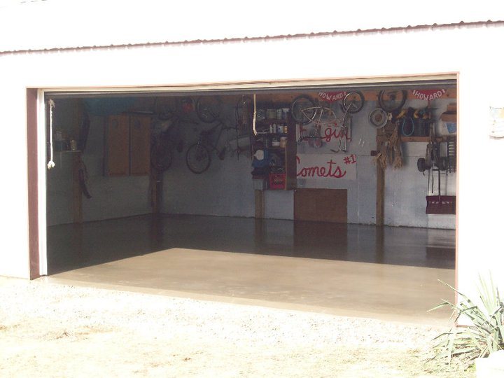Newly poured smooth gray concrete floor slab filling the interior of a metal pole-barn garage.