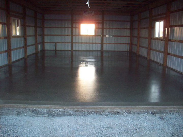 A glossy gray epoxy-coated concrete floor inside a wood-framed metal pole barn garage.