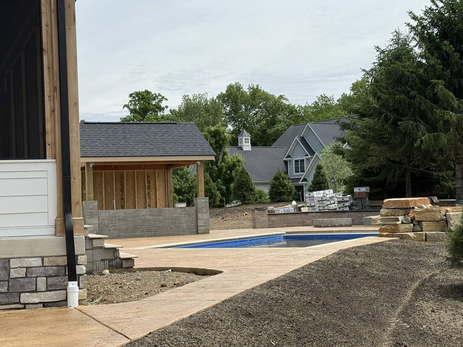 Stamped concrete pool deck and walkway with a retaining wall and covered pavilion.