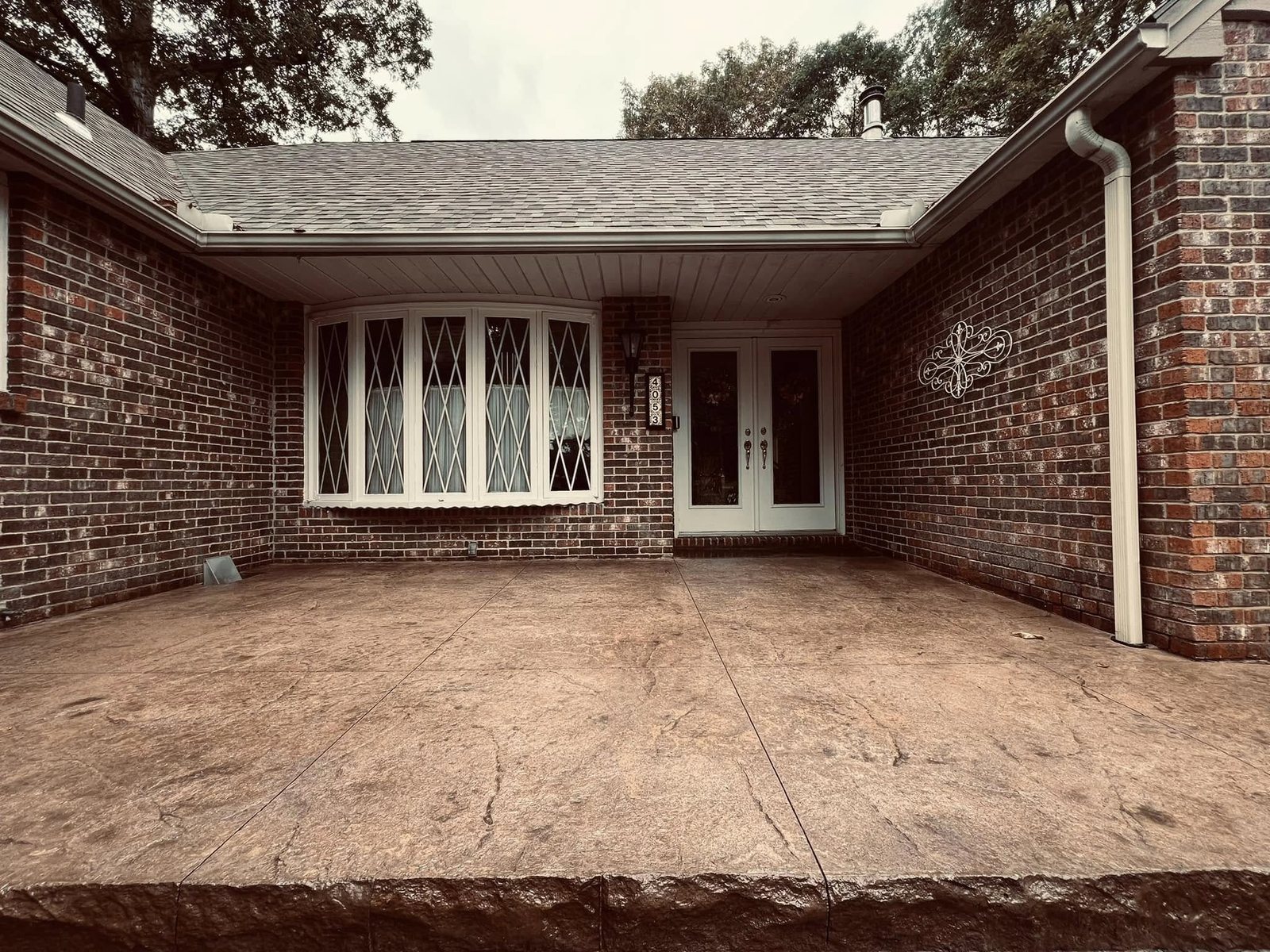 Reddish-tan stamped concrete courtyard patio at a brick ranch entrance.